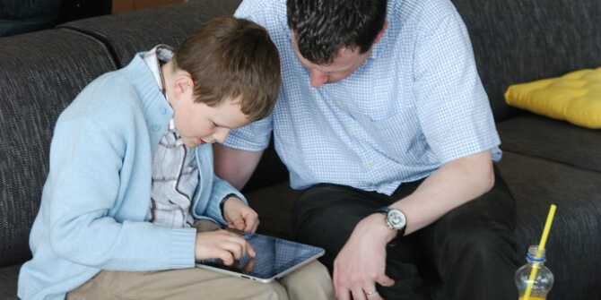 Adult and child leaning over electronic tablet device